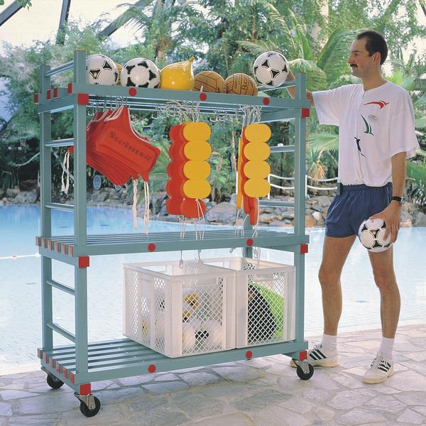 Mann neben Sportwagen mit Fußbällen, Basketball, Schwimmhilfen und Trainingsausrüstung am Pool.