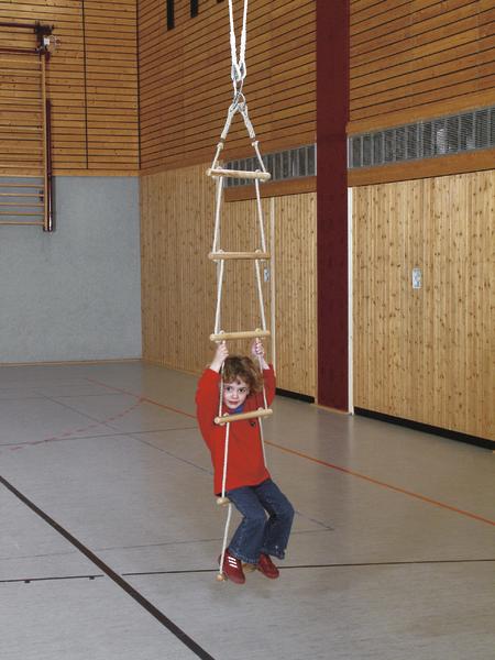Kind schwingt an einer Strickleiter in einer Turnhalle mit Holzverkleidung.