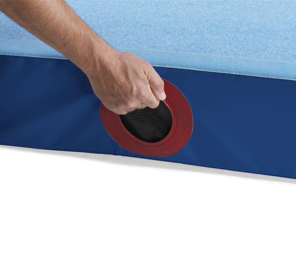 Hand greift in Trageöffnung einer blauen Niedersprungmatte.