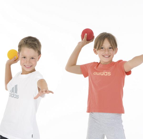 Zwei Kinder werfen bunte Bälle, sportliche Kleidung, weißer Hintergrund, fröhlich und aktiv.