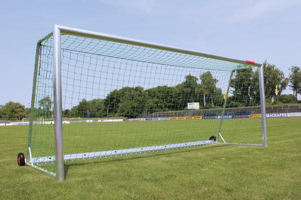 Mobiles Fußballtor mit grünem Netz auf Rasenplatz bei klarem Himmel.