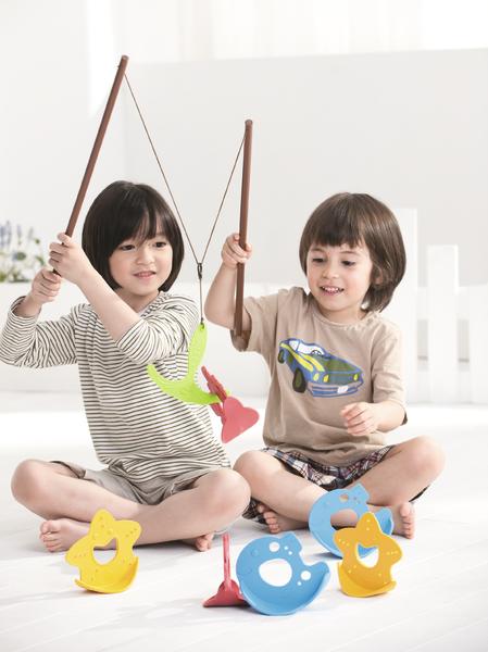 Zwei Kinder spielen mit magnetischem Angelspiel und bunten Tierfiguren auf hellem Boden.