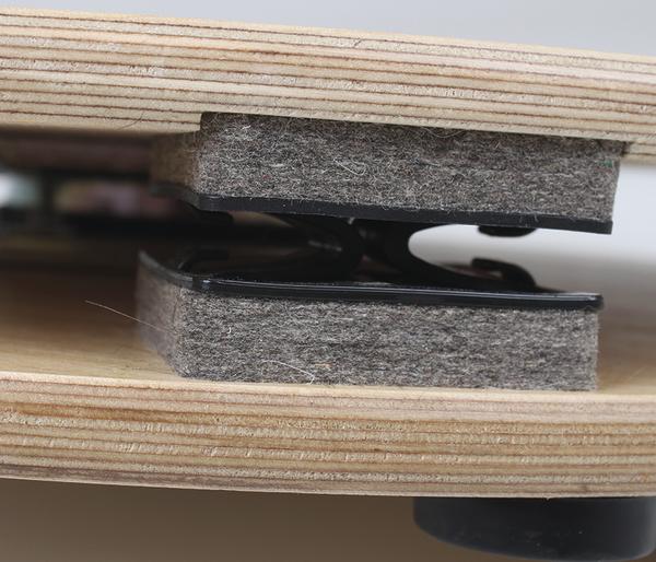 Nahaufnahme von Filzgleitern zwischen zwei Holzplatten.