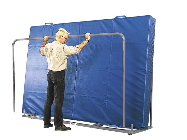 Mann faltet blauen Turnmattenständer mit großen Gymnastikmatten für Sport und Training.