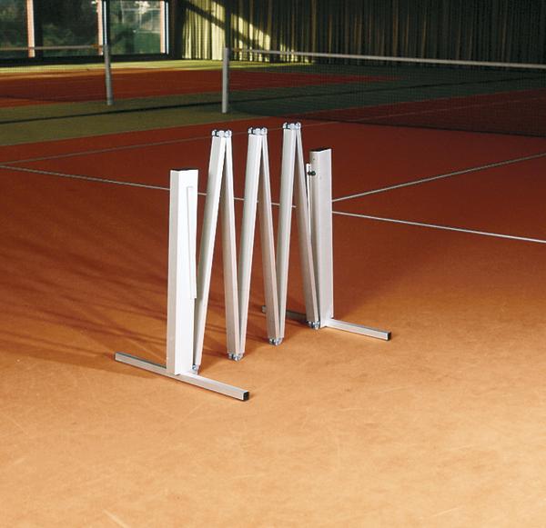 Faltbare Tennisnetz-Abspannvorrichtung auf rotem Sandplatz in Tennishalle.