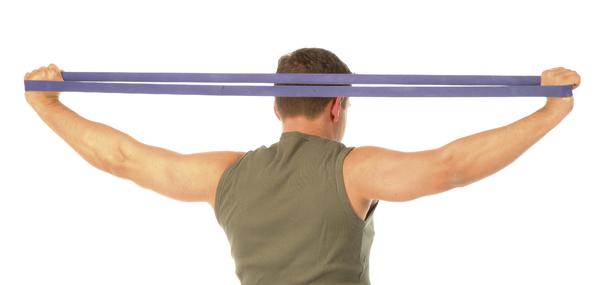 Mann trainiert mit Widerstandsband für Schulter- und Rückenmuskulatur, Rückenansicht.