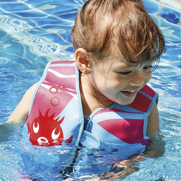 Kind mit Schwimmweste spielt fröhlich im klaren Wasser eines Schwimmbeckens.