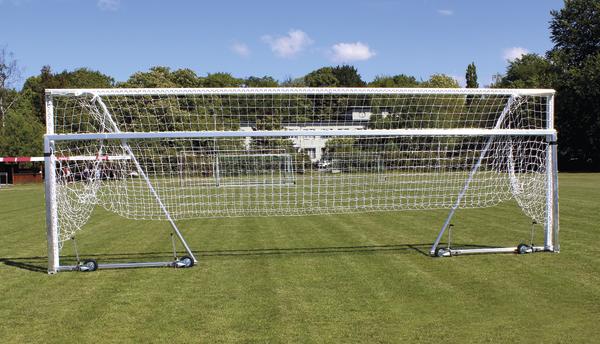 Fußballtore unterschiedlicher Größe auf grünem Spielfeld bei klarem Himmel.