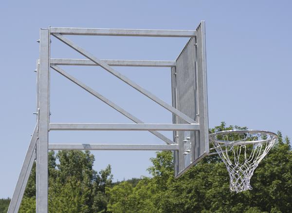 Basketballkorb aus Metall mit Netz vor blauem Himmel und grünen Bäumen im Hintergrund.
