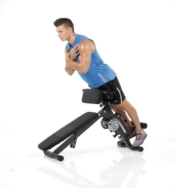 Mann trainiert Rücken und Bauchmuskeln auf einer römischen Bank im Fitnessstudio.