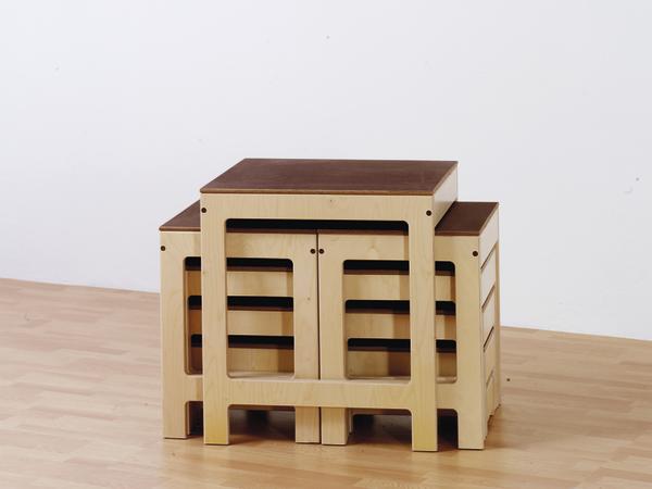 Set aus drei ineinander stapelbaren Holzhockern mit braunen Sitzflächen auf hellem Boden.