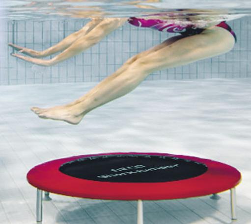 Unterwasseraufnahme einer Person, die auf einem roten Trampolin im Schwimmbecken springt.