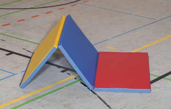 Mehrfarbige Gymnastikmatte in Dreiecksform auf Hallenboden mit Sportlinien.