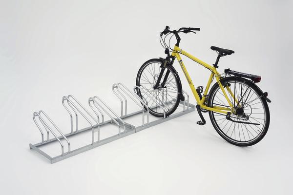 Gelbes Fahrrad steht in einem silbernen Fahrradständer mit mehreren Stellplätzen auf weißem Hintergrund.