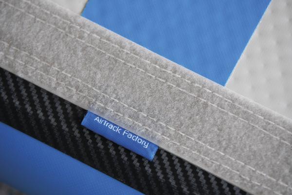 Nahaufnahme eines AirTrack Factory Turnmatten-Etiketts auf blau-weißem Turnmattenstoff.