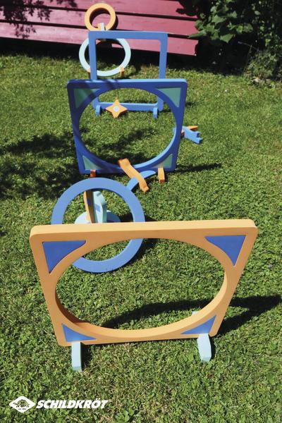 Bunte Hindernisparcours aus Holz für Hundetraining auf grünem Rasen im Freien.