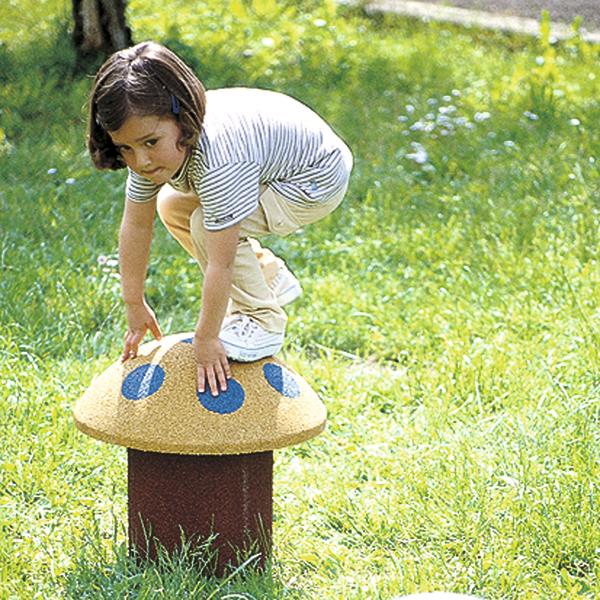 Kind balanciert auf einem pilzförmigen Spielplatz-Element im grünen Park.