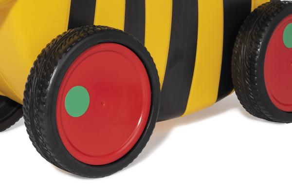 Nahaufnahme von roten Rädern an einem gelb-schwarz gestreiften Kinderfahrzeug.