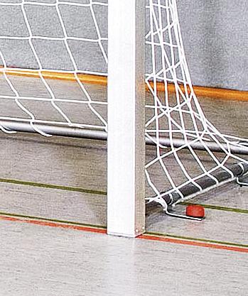 Eishockey-Puck im Tor hinter dem weißen Torpfosten auf Hallenboden mit Netz.