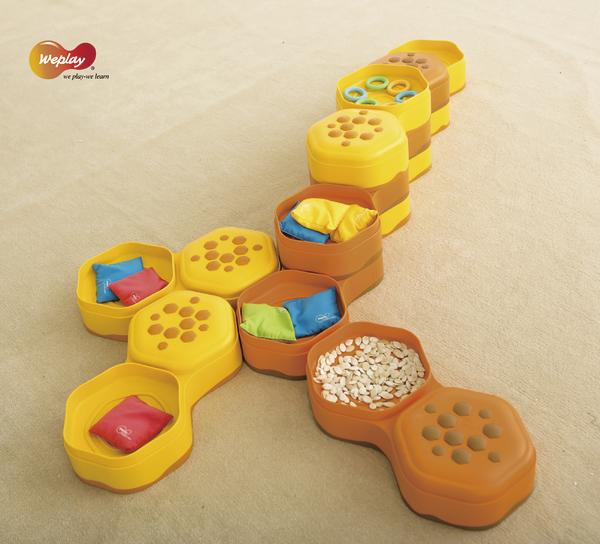 Bunte Stapelbehälter mit verschiedenen Füllungen als Lernspielzeug auf hellem Untergrund.