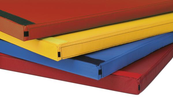 Mehrfarbige Gymnastikmatten gestapelt, rot, gelb, blau, für Sport und Fitness.
