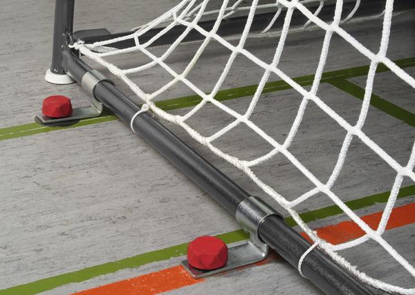 Handballtor-Netz mit Bodenbefestigung und farbigen Hallenlinien auf grauem Boden.