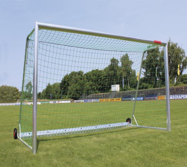 Mobiles Fußballtor mit grünem Netz auf Rasenplatz bei klarem Himmel.
