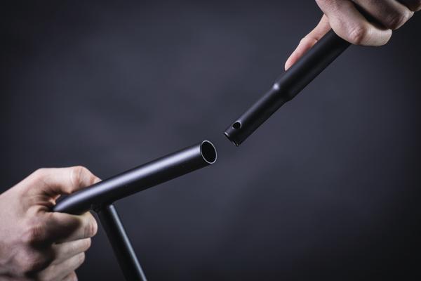 Zusammenstecken von zwei schwarzen Metallrohren vor dunklem Hintergrund.