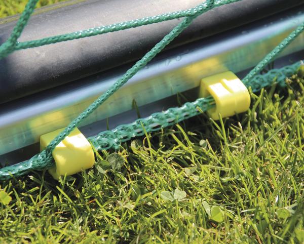 Tornetz mit grüner Schnur und gelben Befestigungen auf grünem Rasen, Nahaufnahme.