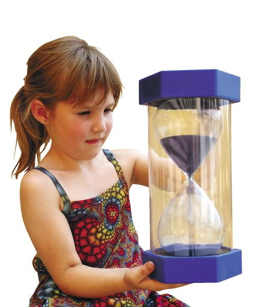 Mädchen hält große blaue Sanduhr mit schwarzem Sand in buntem Kleid.