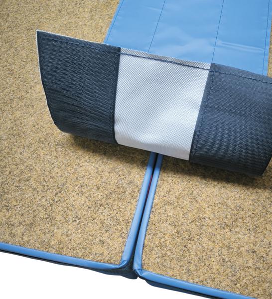 Verbindung zweier blauer Schaumstoffmatten mit Klettverschluss auf Teppichboden.