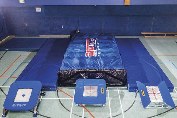 Trampolin-Sprungmatten und Airtrack-Matte in einer Sporthalle für Turnübungen.