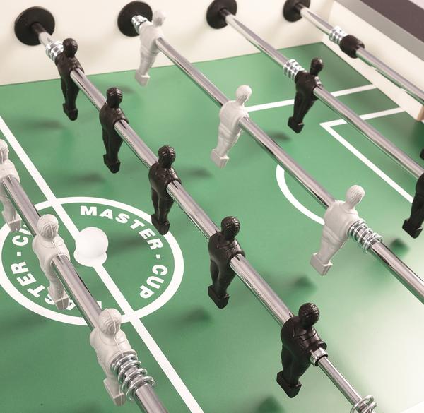 Spielfiguren aus Kunststoff auf verchromten Stangen über grünem Kickerspielfeld.