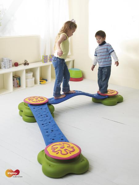 Kinder balancieren auf einem bunten Indoor-Spielplatz-Set aus Kunststoff.