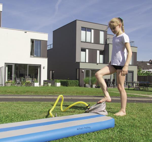 Mädchen pumpt das AirBeam in blau mit einer Fußpumpe im Freien auf.