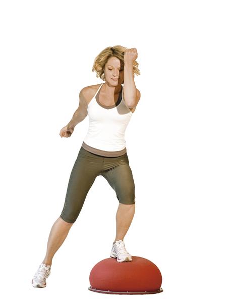 Frau trainiert Balance und Koordination auf einem halbrunden Balance-Board in Sportkleidung.