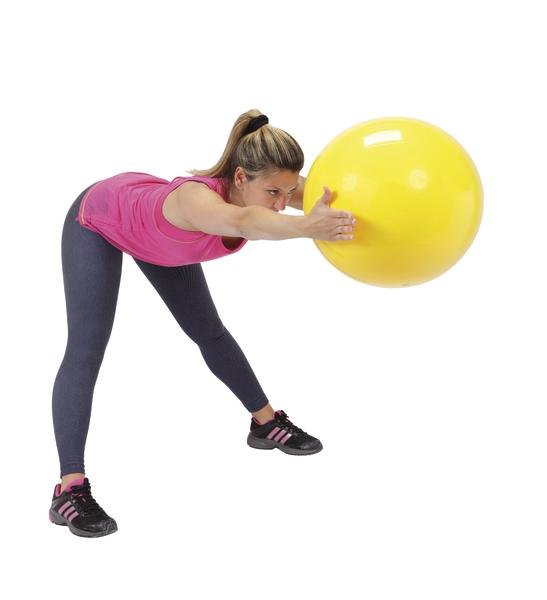 Frau trainiert mit gelbem Gymnastikball, Fitnessübung im Stehen, weißer Hintergrund.