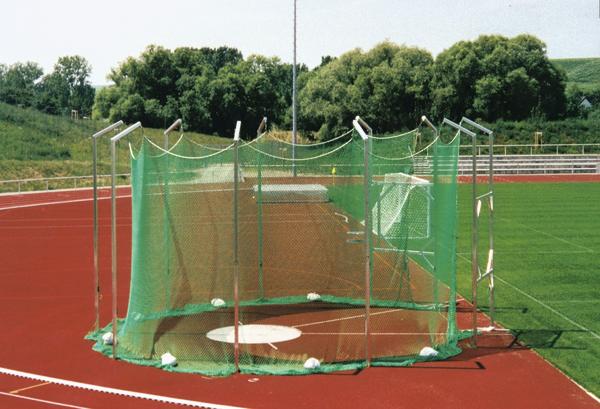Hammerwurfanlage mit grünem Schutznetz auf roter Laufbahn im Freien bei Sonnenschein