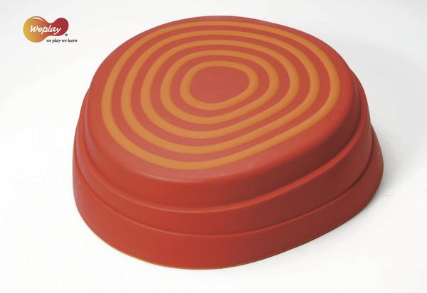 Rotes Balancierkissen mit orangefarbenen konzentrischen Kreisen für Gleichgewichtstraining.