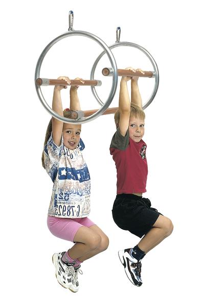 Kindermädchen hängen an Turnringen und trainieren Kraft und Koordination.