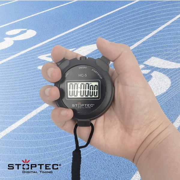 Schwarze Stoptec Stoppuhr HC-5 mit digitalem Display in einer Hand vor einer blauen Laufbahn.