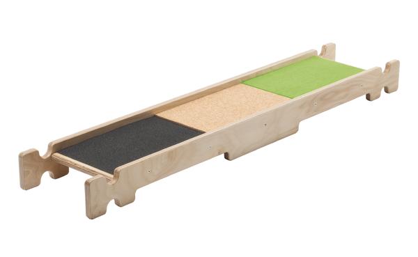 Barfußpfad aus Holz mit drei verschiedenen Oberflächen in Schwarz, Beige und Grün, taktil.