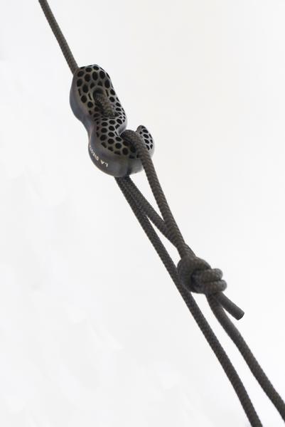 Schwarzes Kletterseil mit Karabiner und Knoten vor weißem Hintergrund.