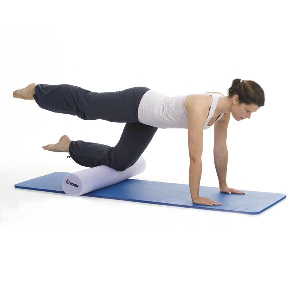 Frau macht Balanceübung auf Schaumstoffrolle mit ausgestrecktem Bein auf Yogamatte.