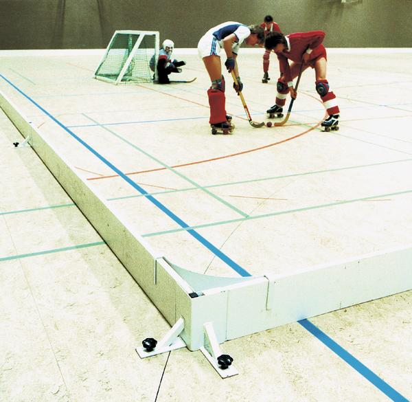 Rollhockey-Spieler kämpfen um den Ball vor dem Tor auf einer Hallenbahn.