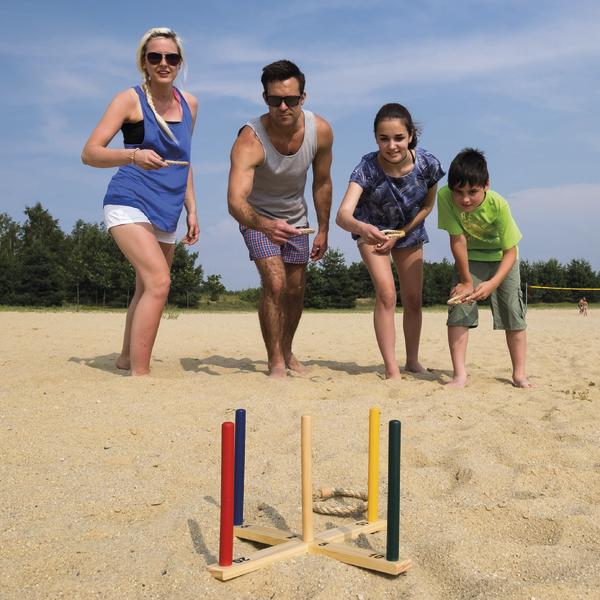 Familie spielt Wikingerschach im Sand an einem sonnigen Tag im Freien.