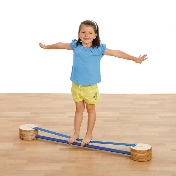 Mädchen balanciert auf blauem Balanciergerät aus Holz auf hellem Boden.