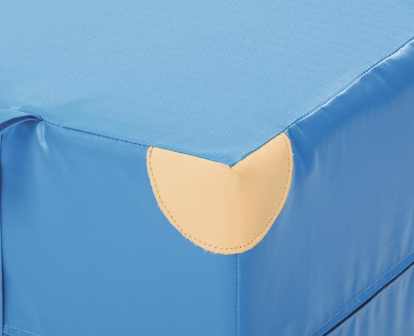Ecke eines blauen Turnmattenstapels mit schützender gelber Ecke aus Leder.