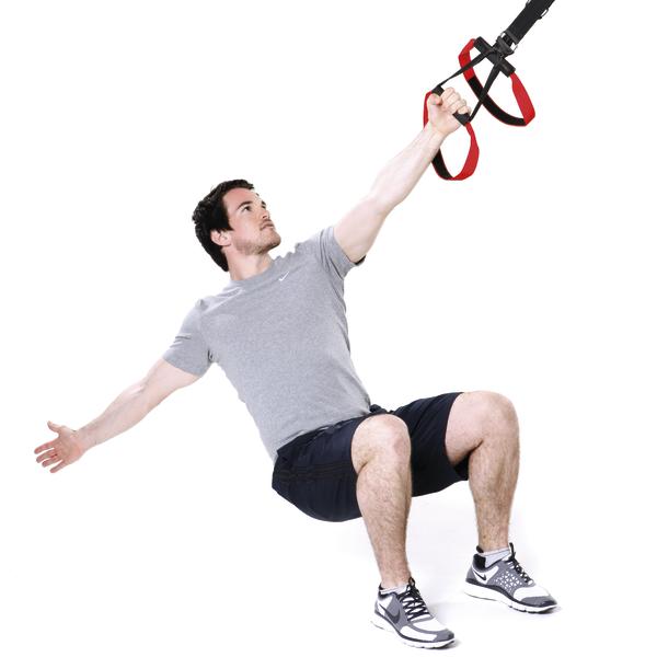 Mann trainiert mit TRX-Bändern in sitzender Position für Kraft und Balance.