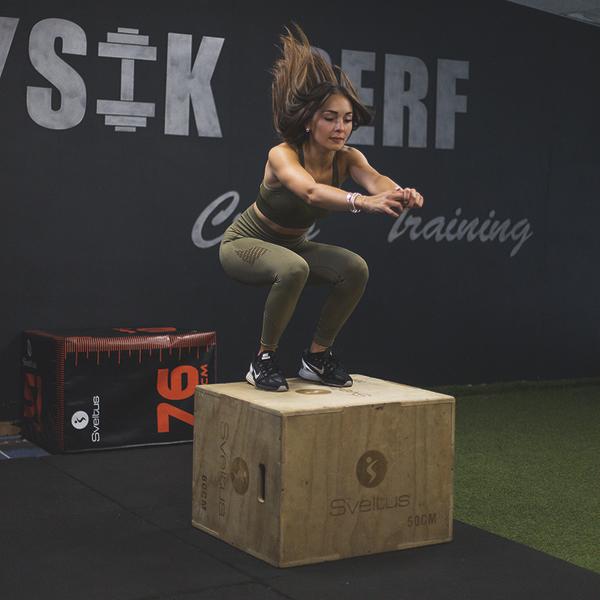 Frau macht Plyo-Box-Jumps im Fitnessstudio für Kraft- und Sprungtraining.